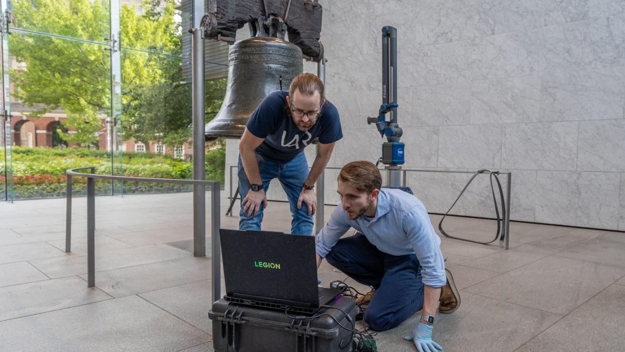 two people working next to the liberty bell