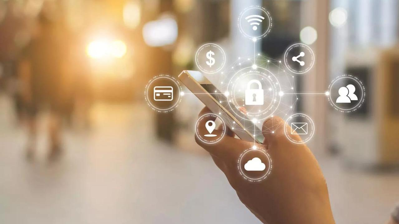 A hand holding a cell phone. Digital icons on top, A key lock is central surrounded by other icons for wifi, share, contacts, email, cloud, location, credit card, and money.