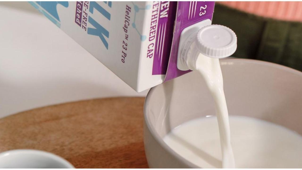 A container of milk being poured into a bowl.
