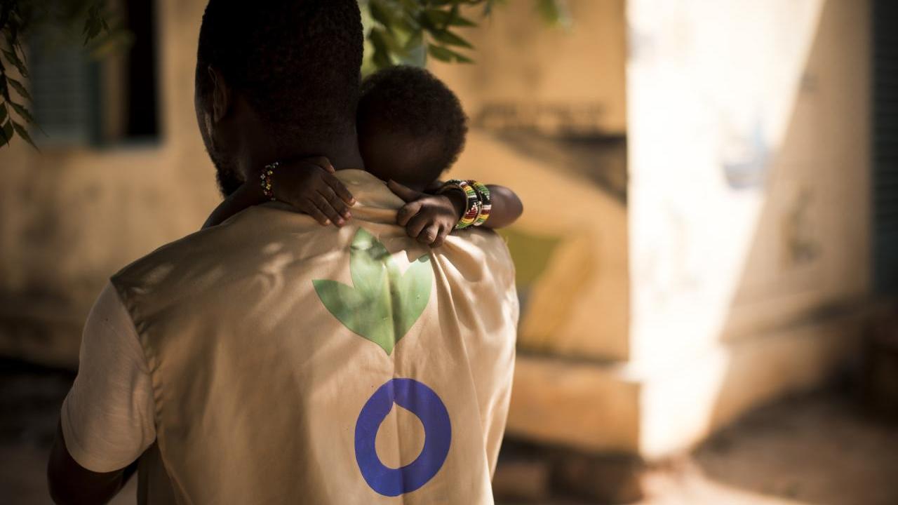 An Action Against Hunger Aid Worker holds a child in his arms in Mali. // Photo by Toby Madden