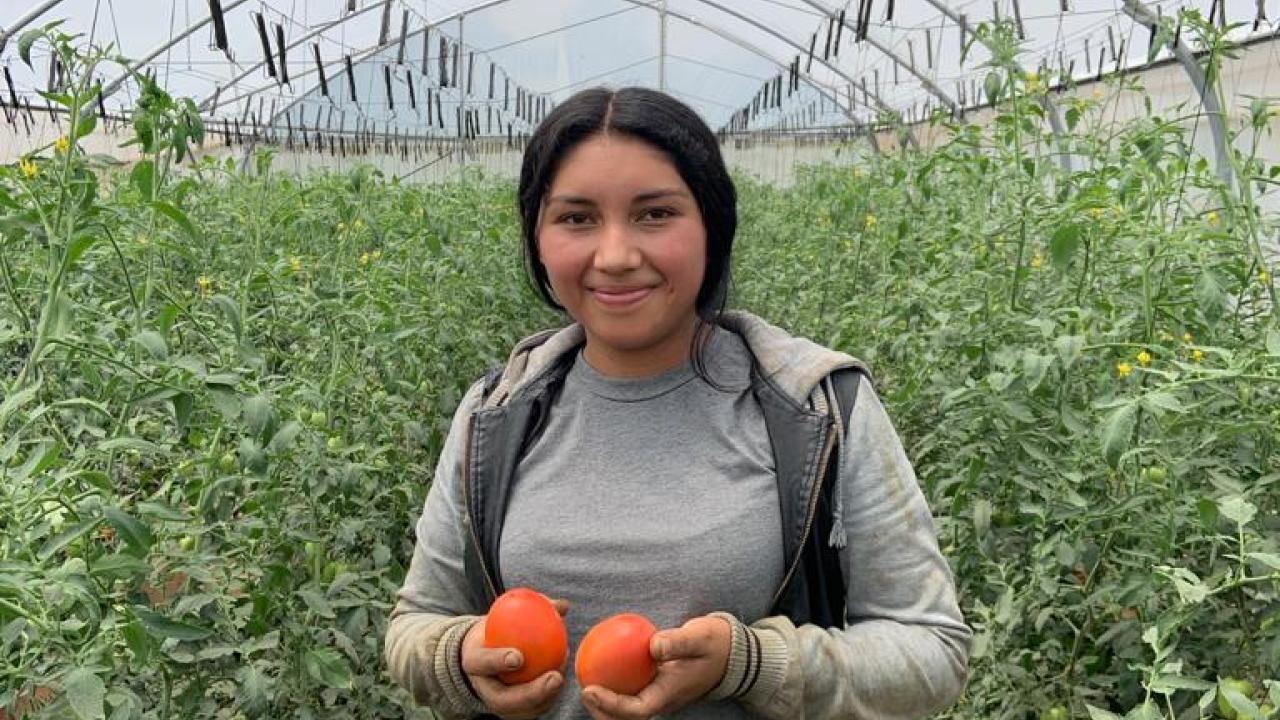 Gloribel holding two tomatoes