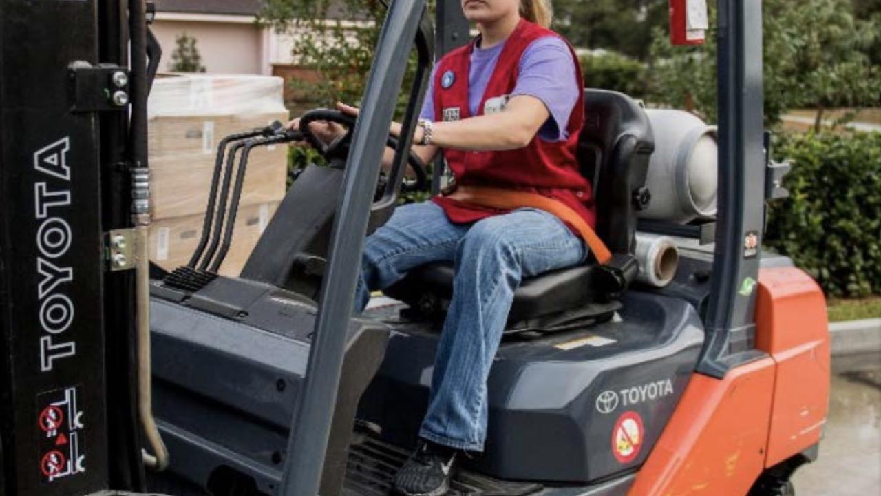 tractor supply employee in a red vest, driving a forklift