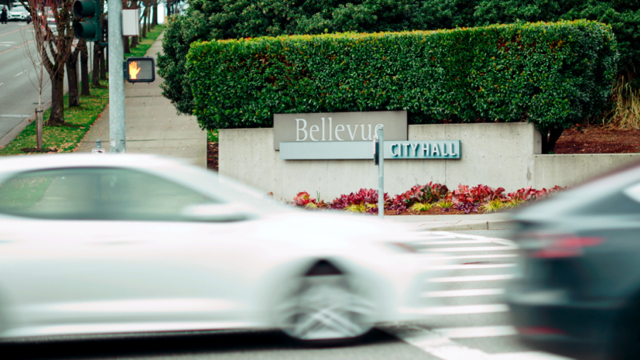 Cars going by on a street in front of a sign "Bellevue"