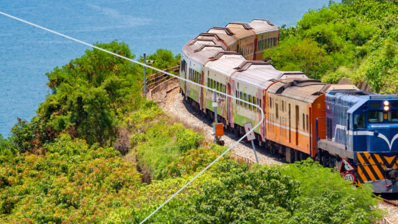 A train going down a track. A coastal scene.