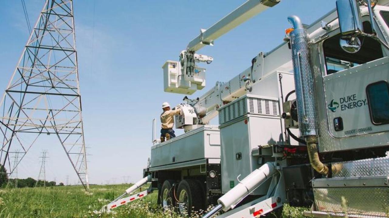 A power utility vehicle parked near tall power-line towers.