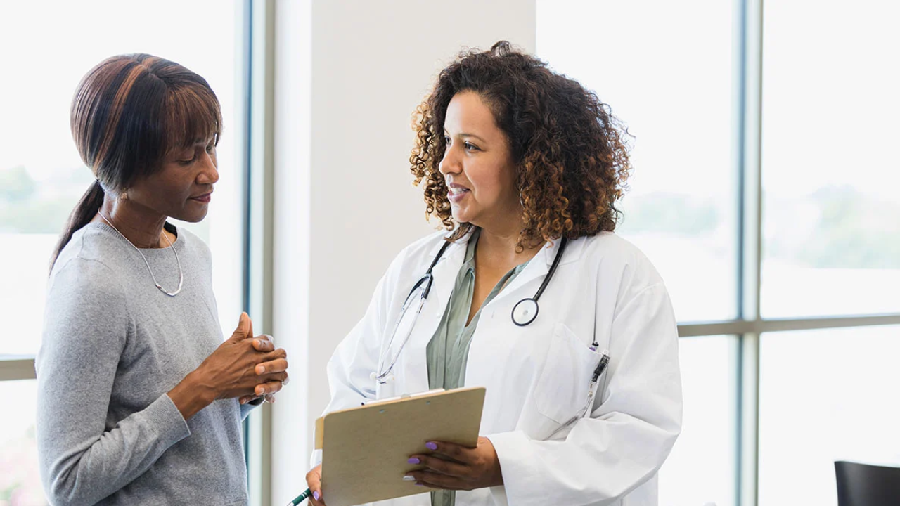 A woman in a lab coat asking questions to a woman