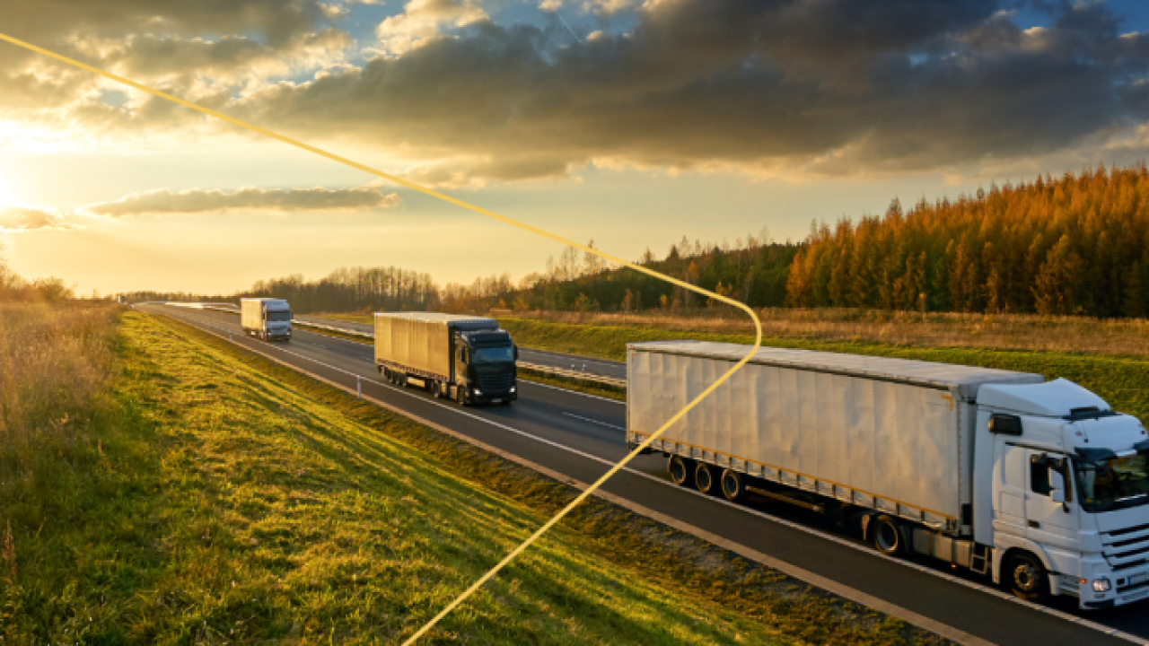Trucks on a road with a setting sun behind them.
