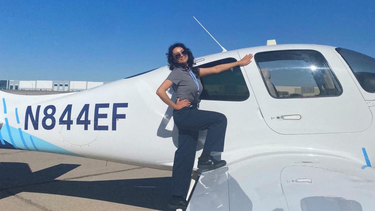 Natalie Villalpando, in sunglasses, stands on the wing of a small plane