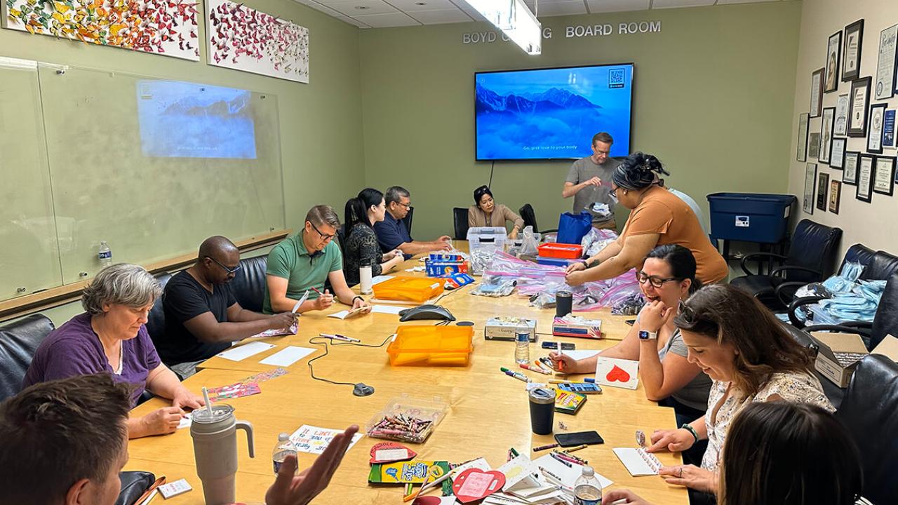 A group seated at a large conference table doing crafts.