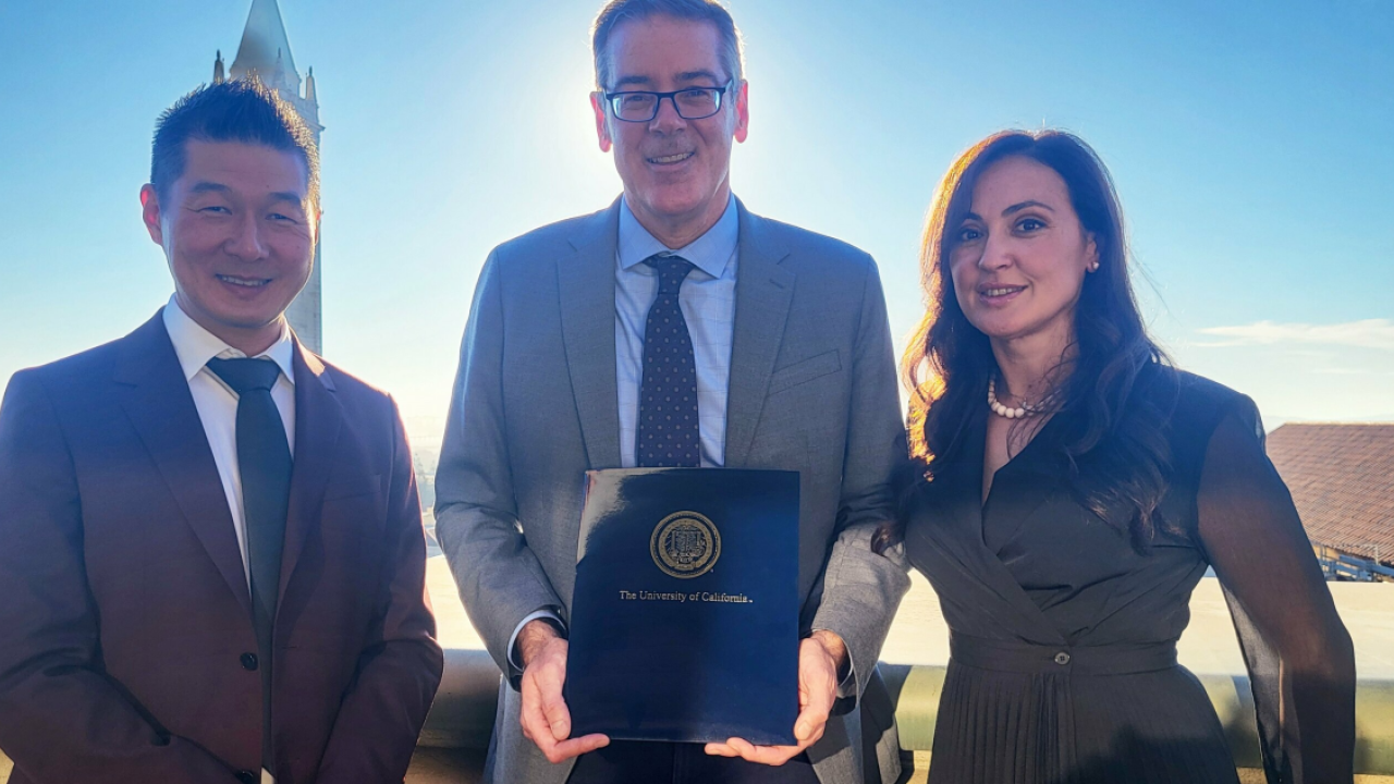 Three people standing together, holding a report