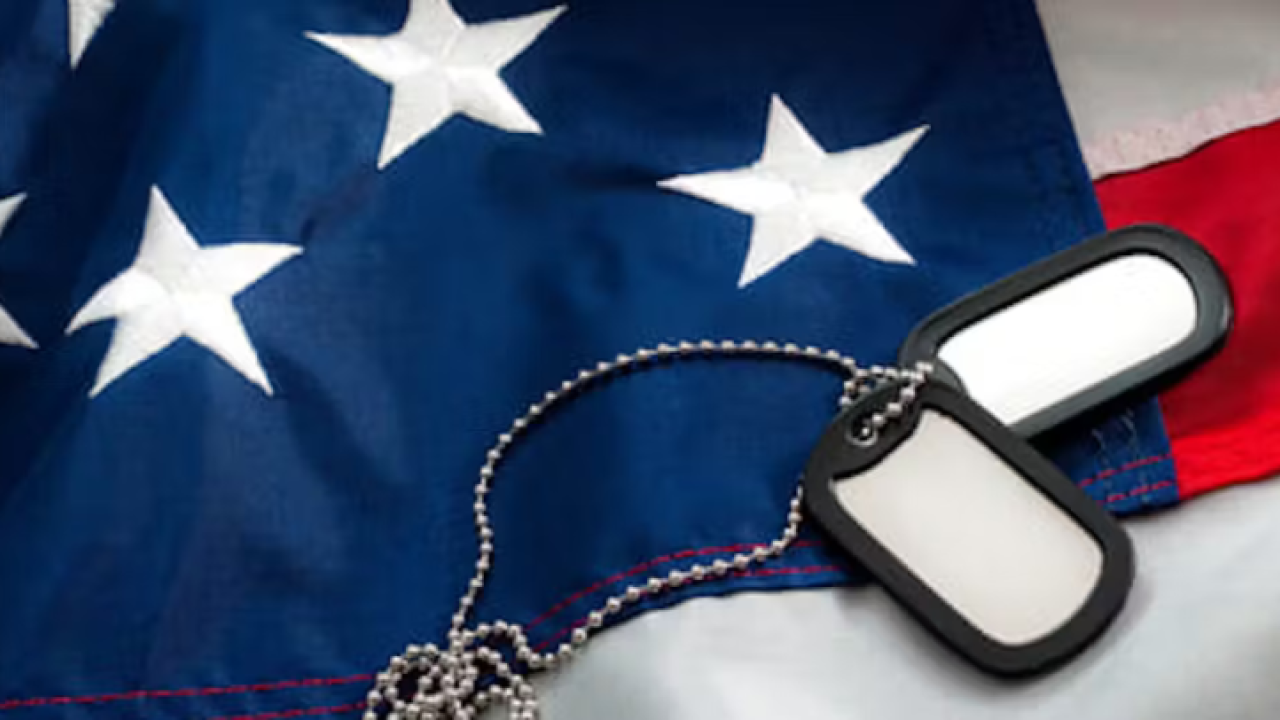 A US flag with 'dog tags' on a chain laid on top.