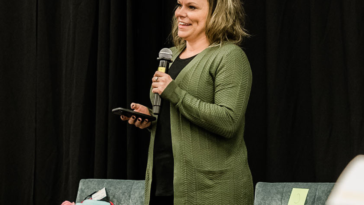 Ashlea Currey in a green cardigan holding a microphone