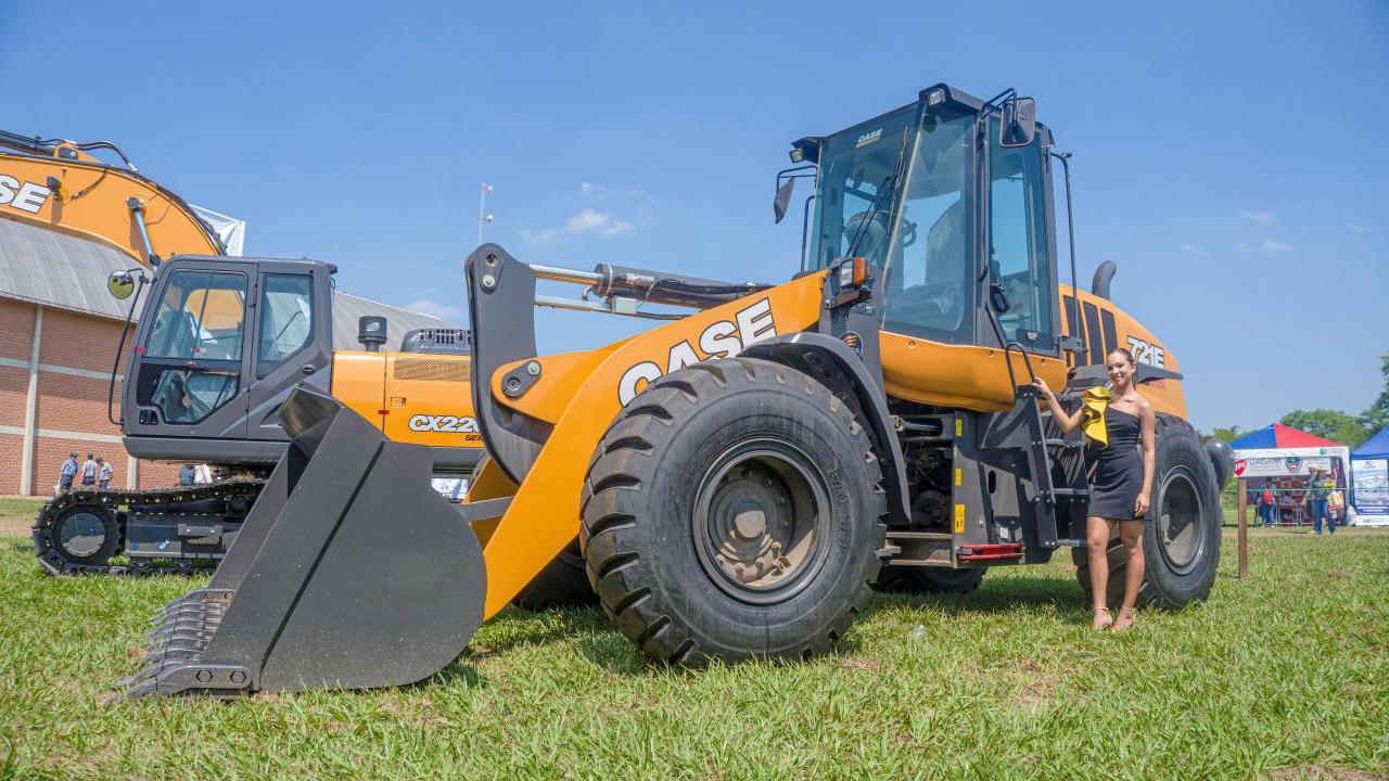 A person standing by a large bucket-style construction vehicle.