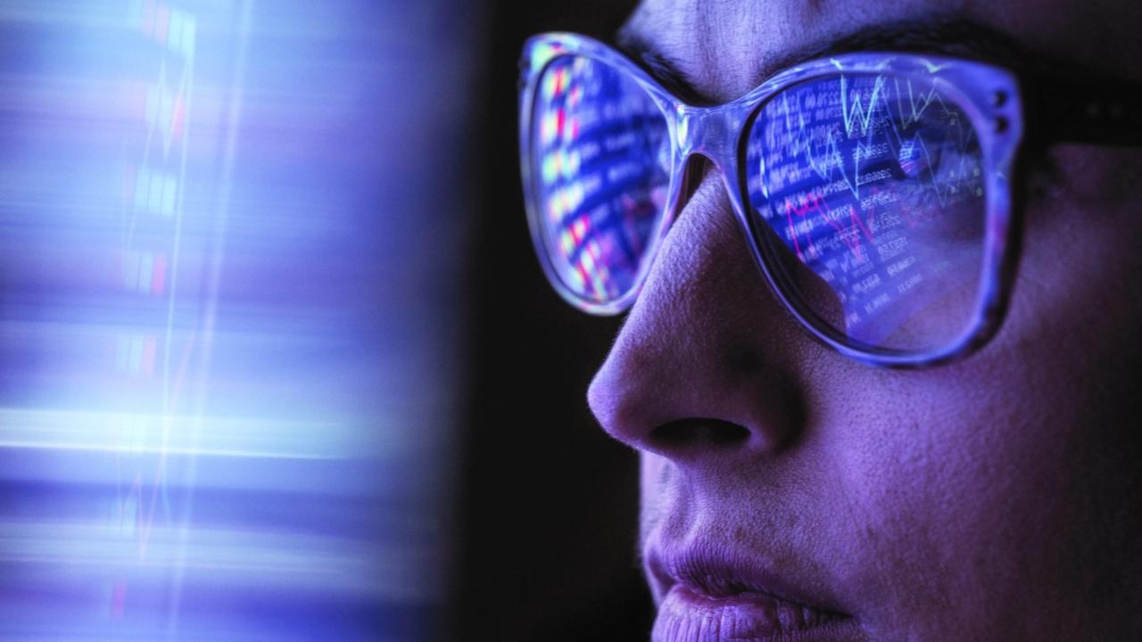 A person wearing glasses, computer data reflected in the lenses.