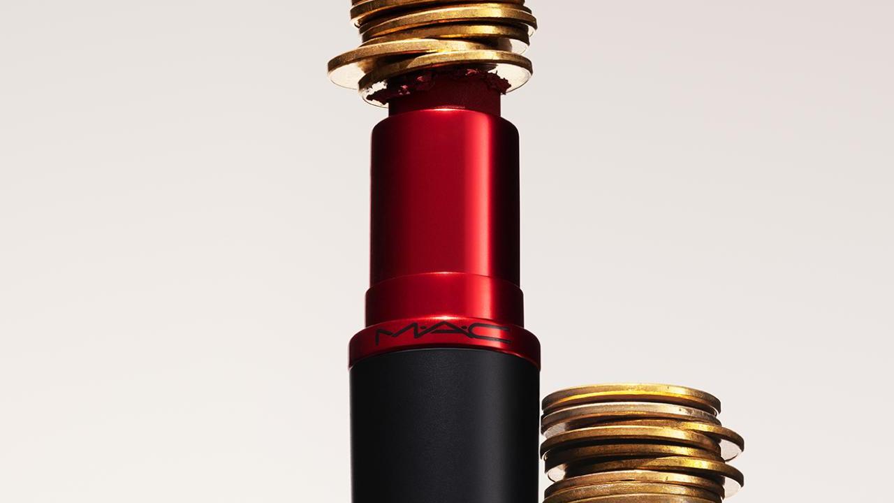 A lipstick with stacked coins in the middle of it and to the side.