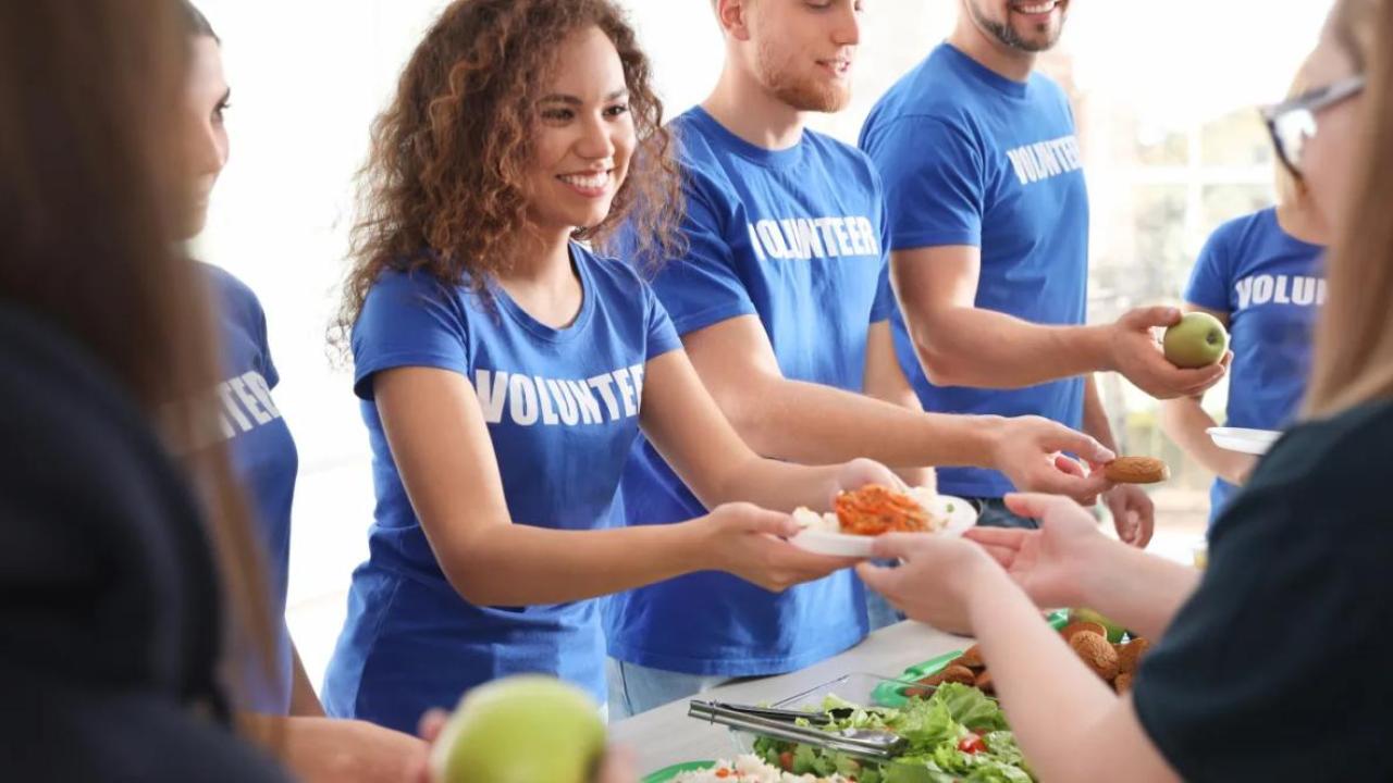 A line of volunteers handing food to others.