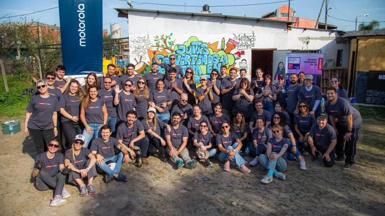 A group of volunteers posed outside a small building. Motorola sign to the side.