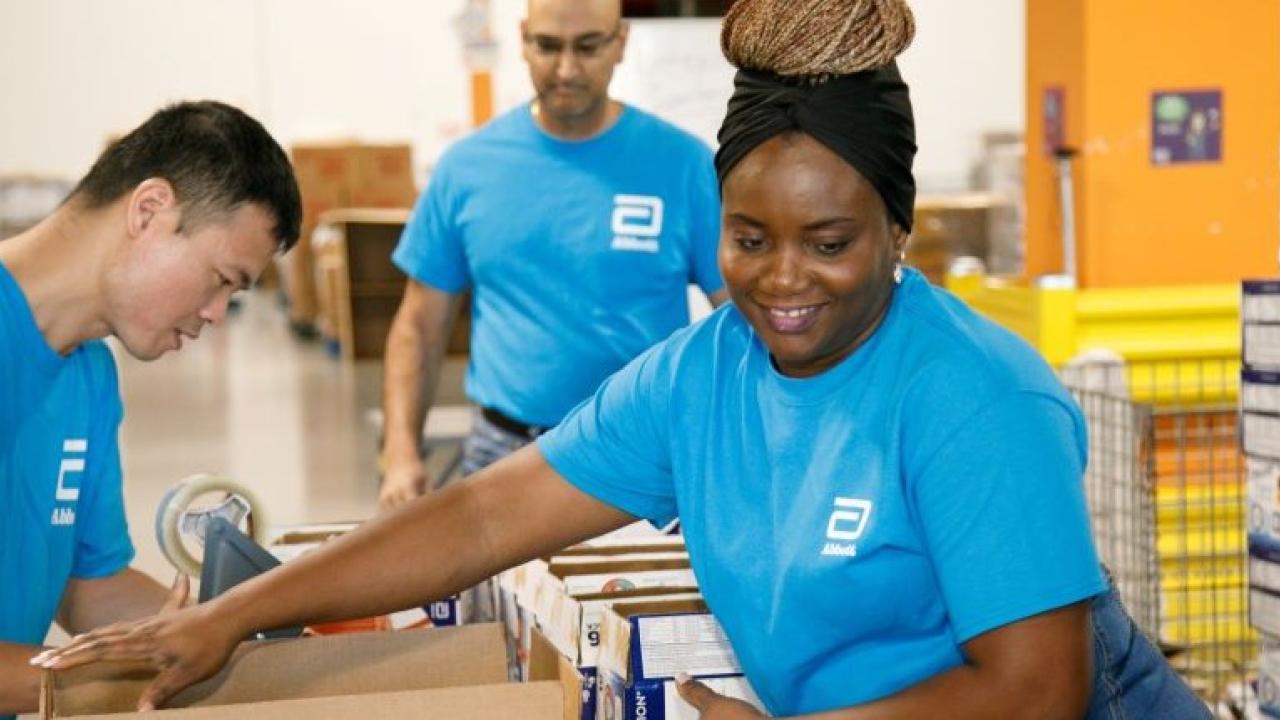 Volunteers in a warehouse setting packing boxes.