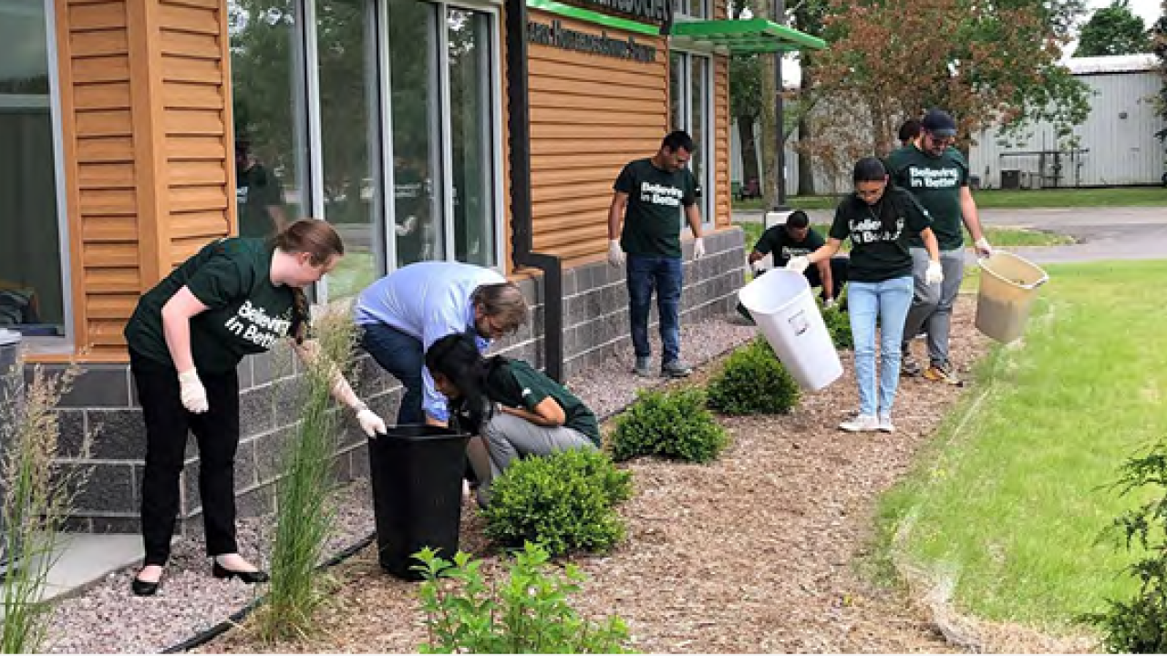 A team of volunteers picking up trash outside a building.