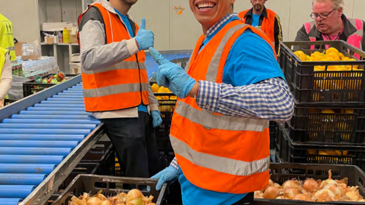 Volunteers with bins of onions, giving thumbs-up to the camera.