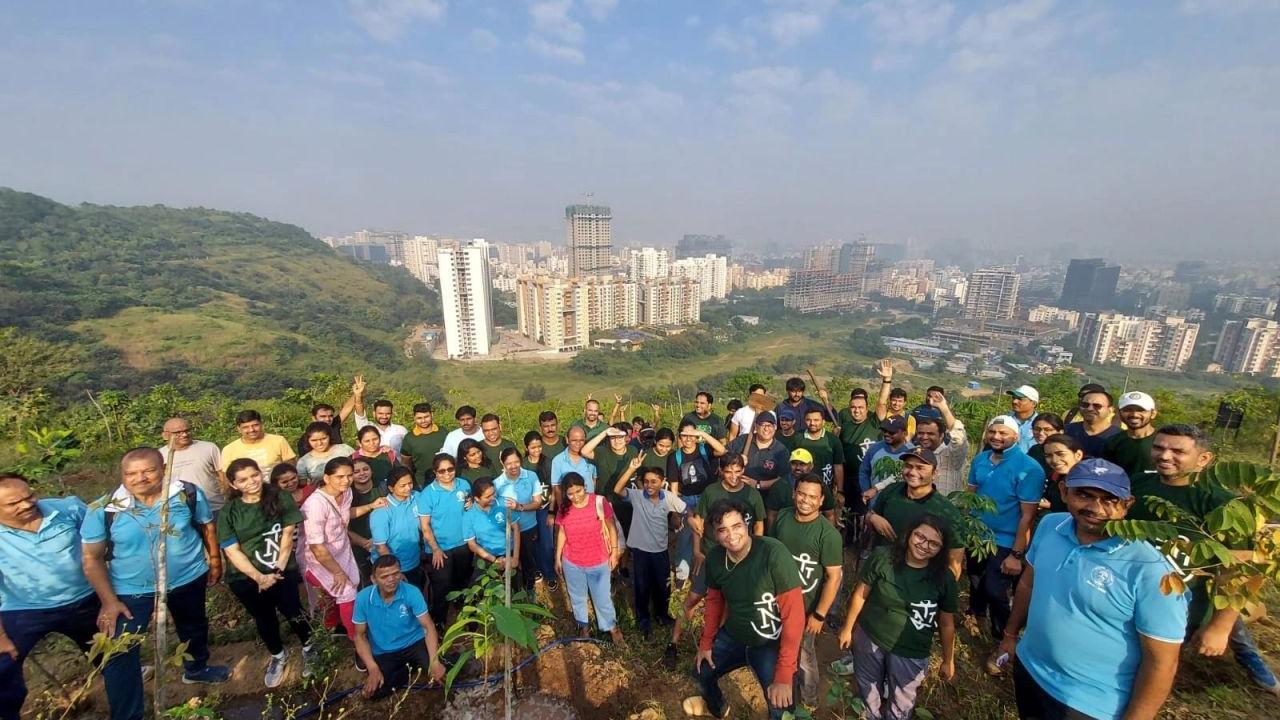 A large group of volunteers posed on a hillside, a city landscape behind them.