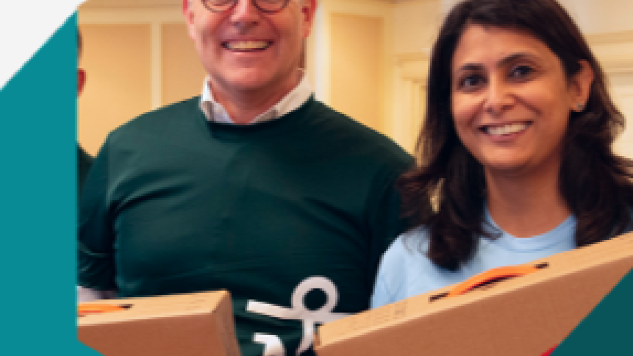 Two smiling people holding boxes.