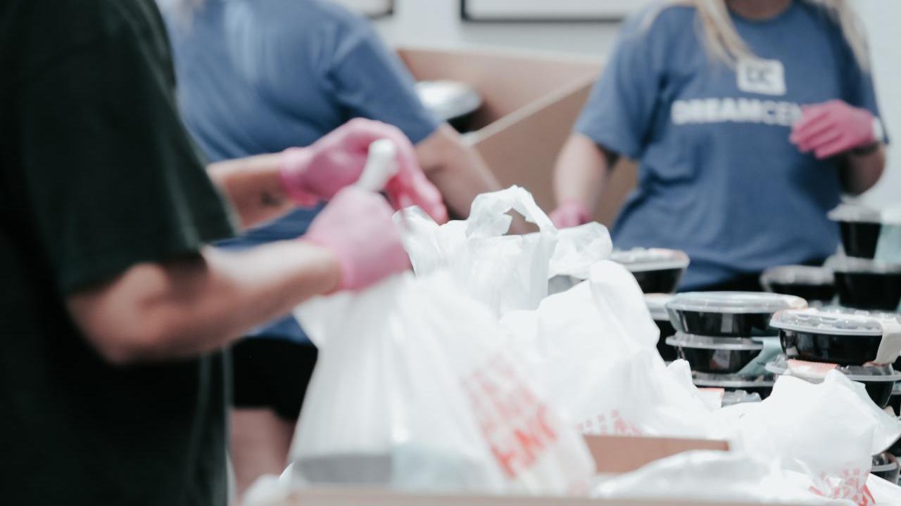 Volunteers packing food item in boxes.