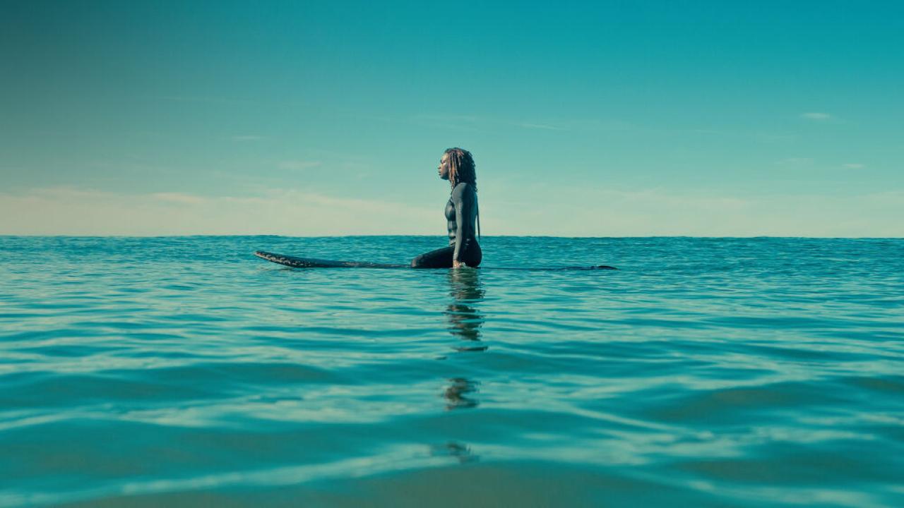 A lone person on a surf board in a large body of water.