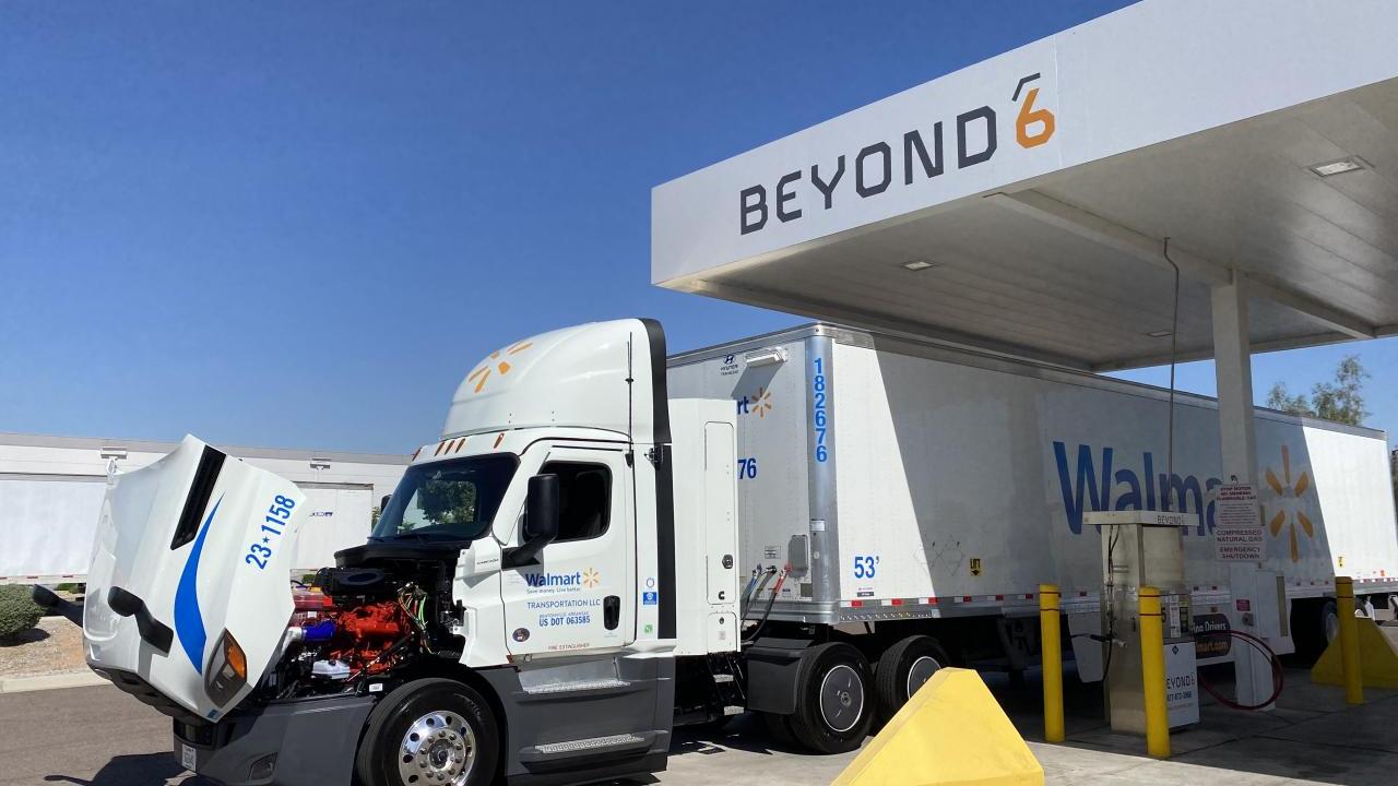 A semi truck with the hood open under an overhang with "Beyond" on it.