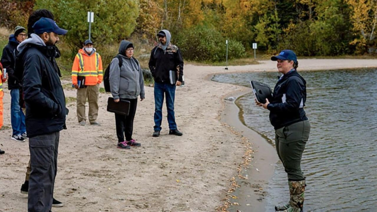 group of people speaking along the edge of a body of water