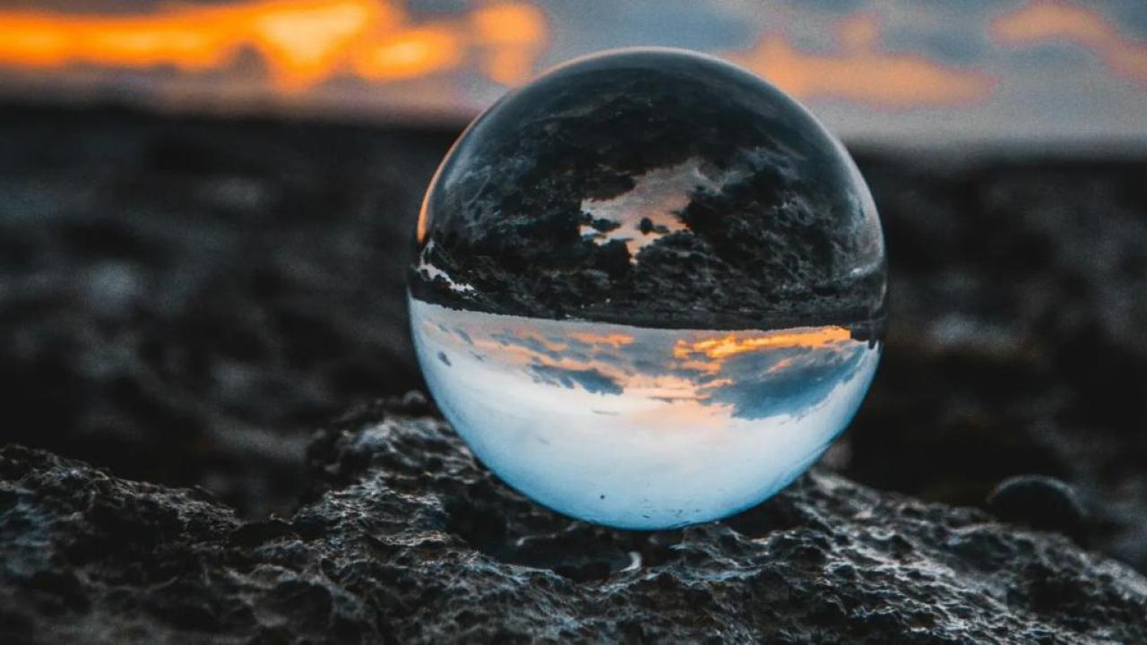 A clear sphere on dark ground. Cloudy sky in the background.