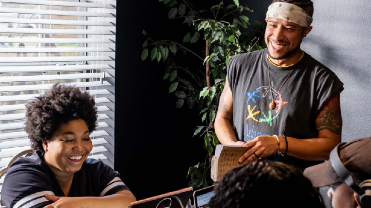 Photo: Werc Crew — XAVIERBLK.COM; people smiling in front of a laptop.