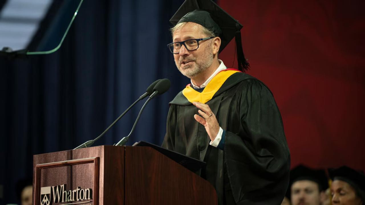 Mike Sievert, CEO of T-Mobile, in a cap and gown at a podium