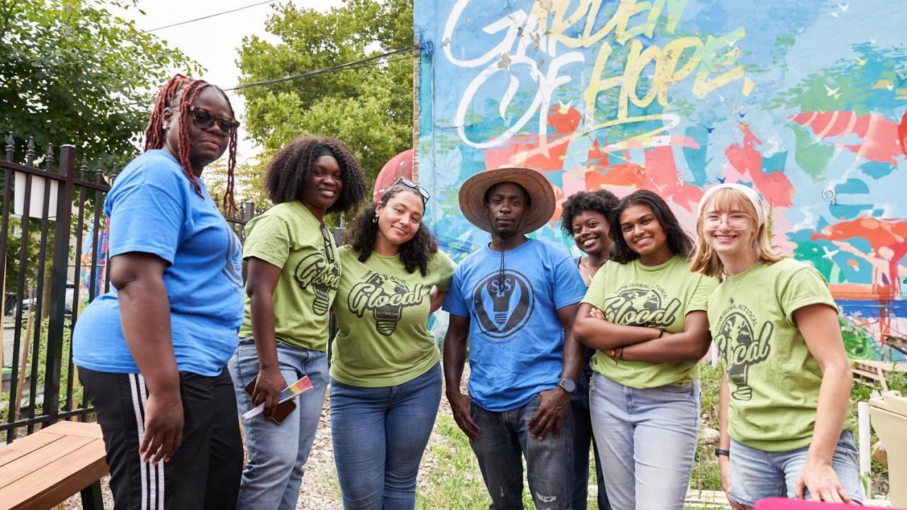 Seven people posing together in a garden: "Garden of Hope"