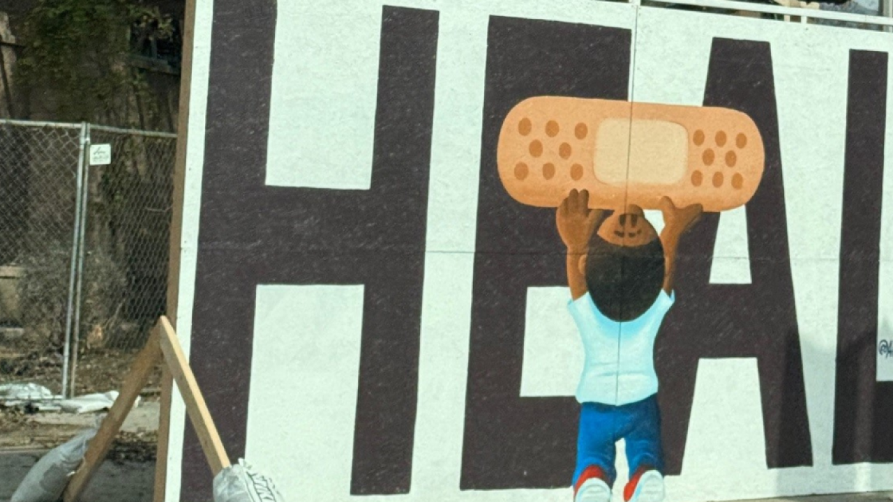 mural with "HEAL" and a child placing a band aid