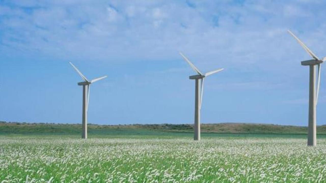 A row of wind turbines in an open field.