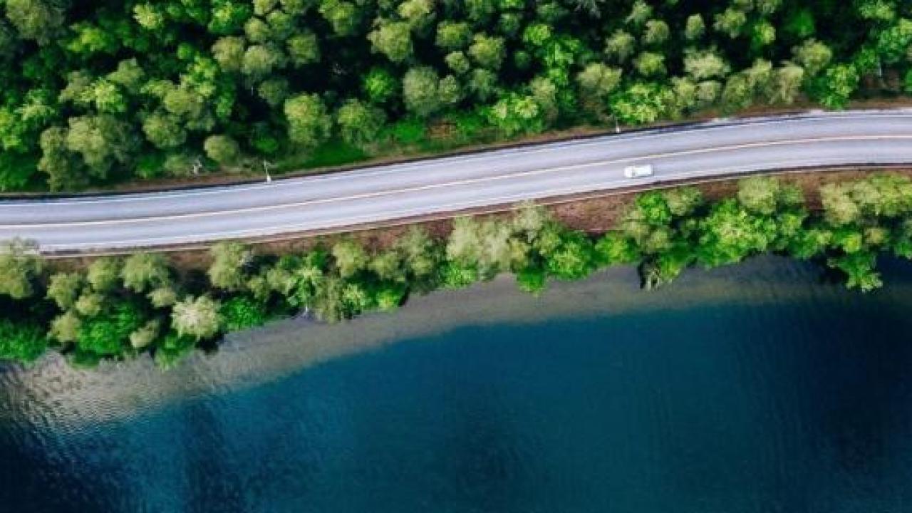Aerial view of cars on a winding coastal road.