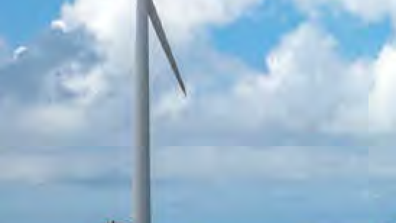 Windmill in an open field, partially cloudy sky