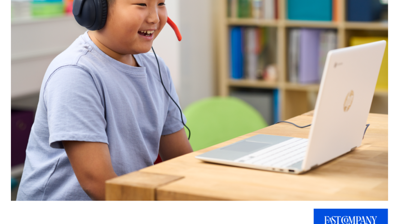 A child with a headset smiling toward a laptop screen