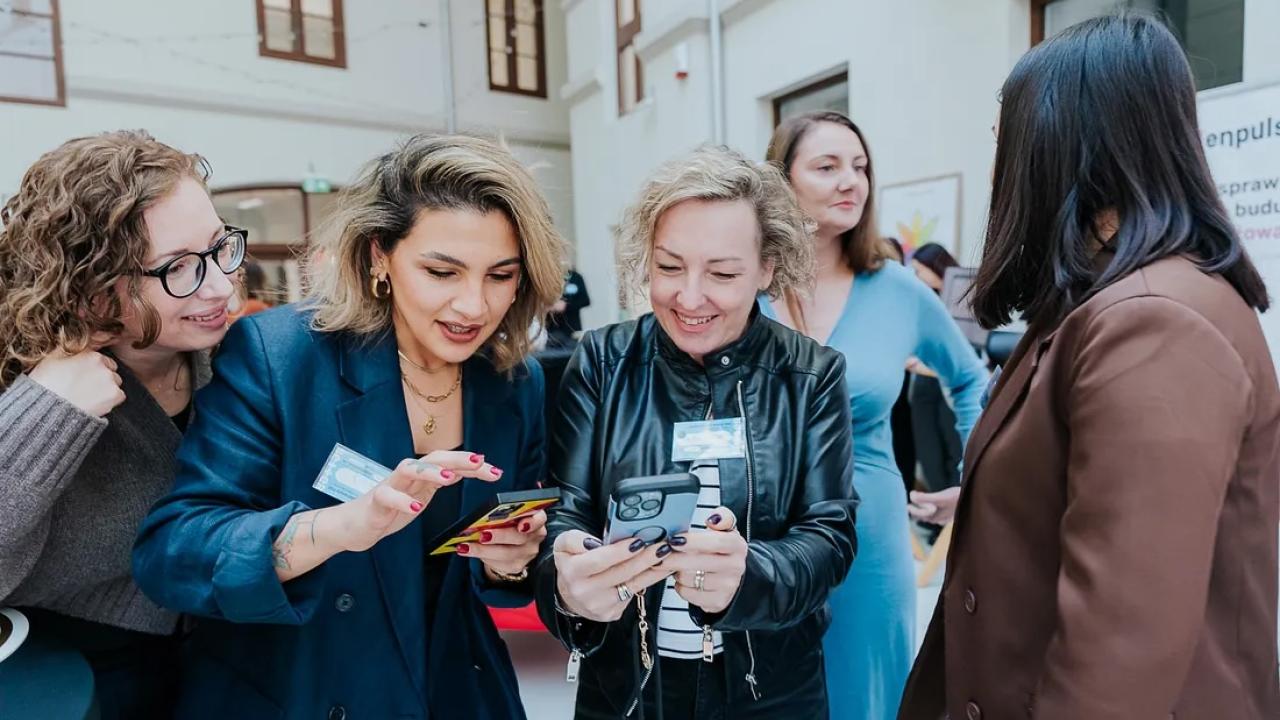 Women dressed in business attire eagerly looking at phones