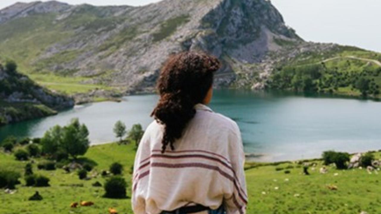 A person looking out over a mountain and lake scenery.
