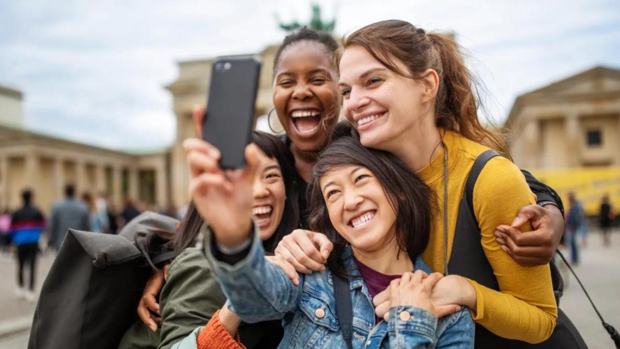 Four smiling people taking a selfie together outside