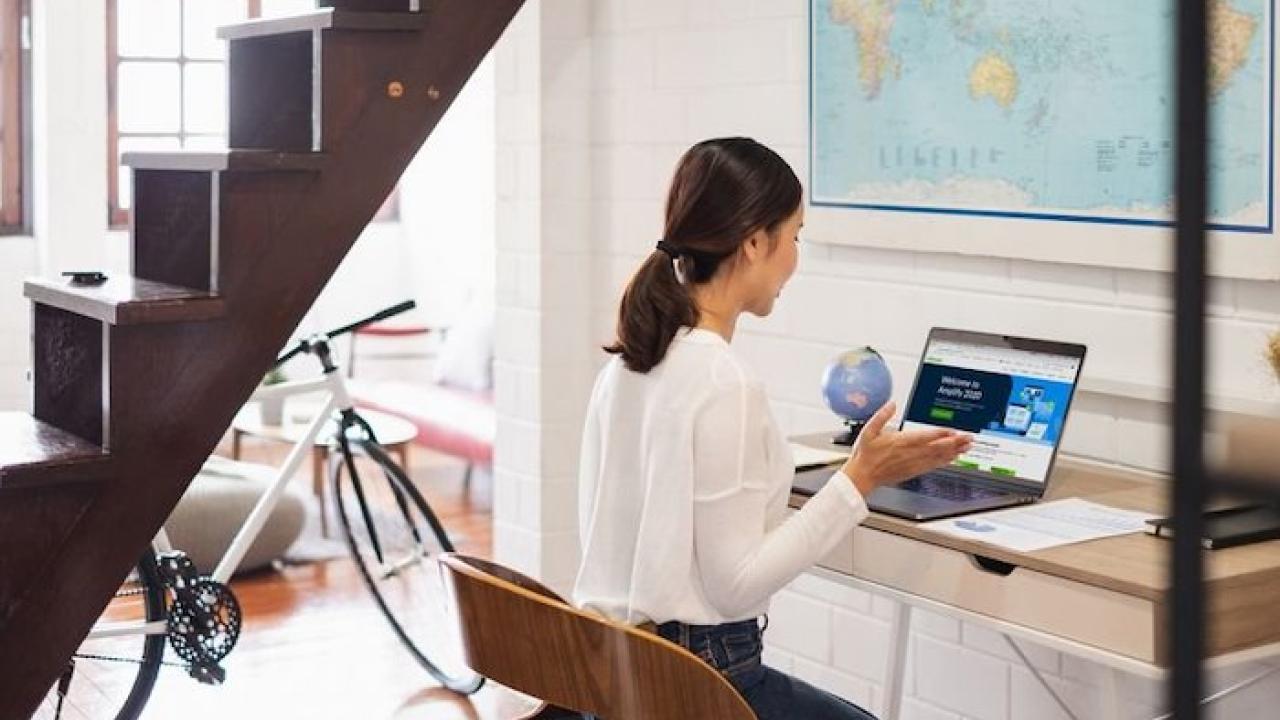 Woman seated at her desk in front of her laptop.