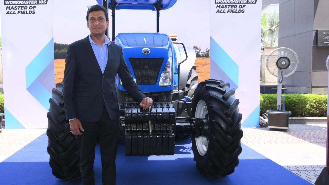 A person standing next to a blue tractor on display.