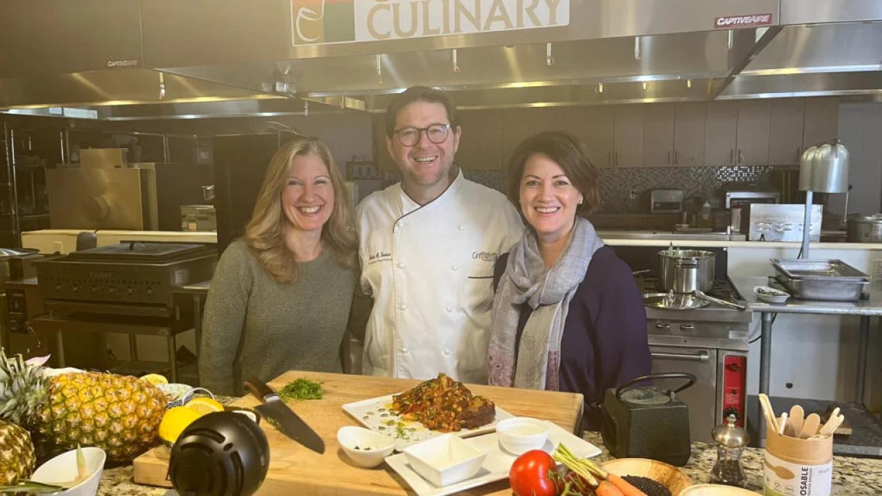 Three people posed in a kitchen.