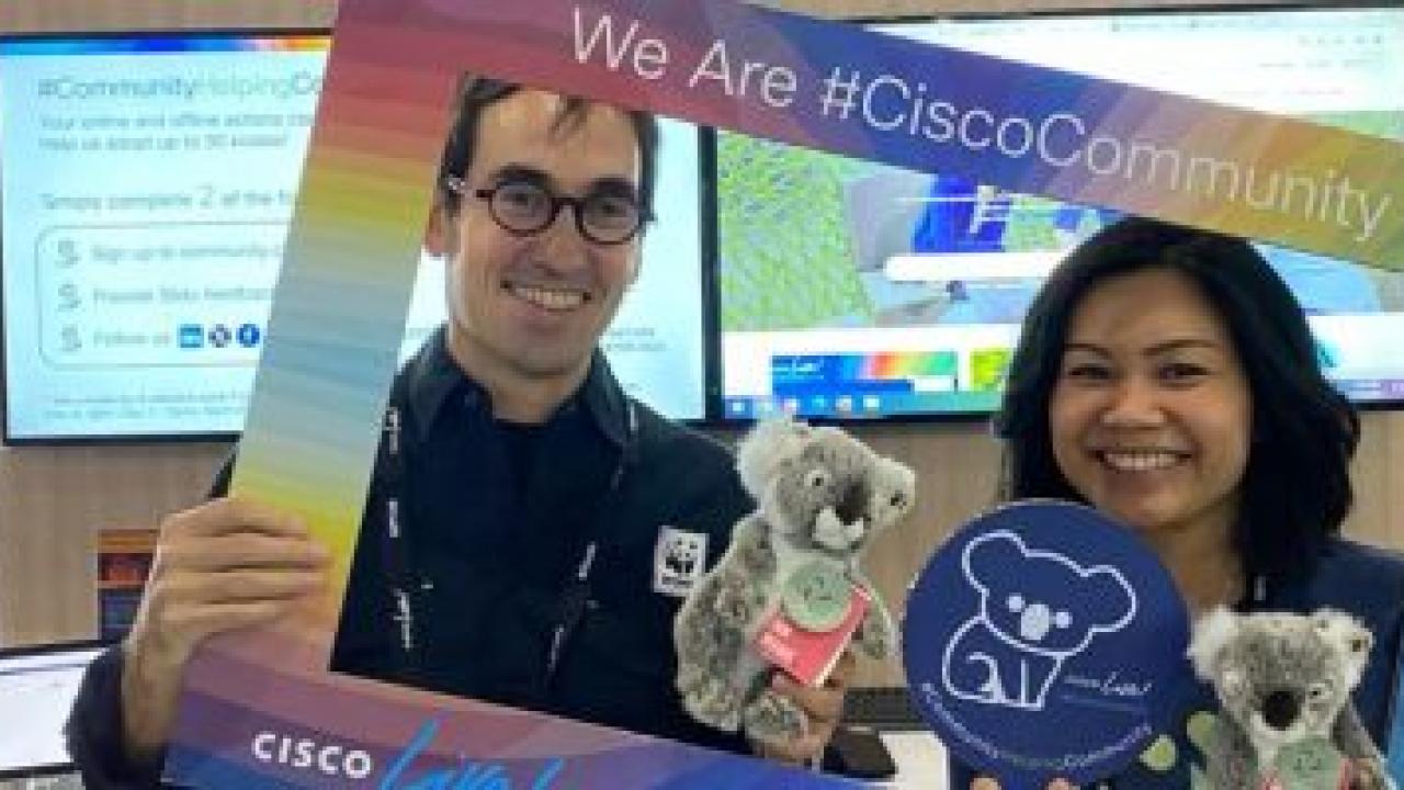 Two people holding up a colorful frame "We Are Cisco Community". Each holding a stuffed koala.