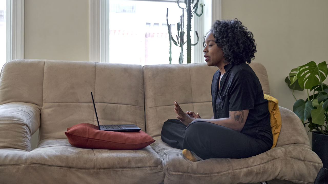 A woman sitting on a couch, in an online meeting