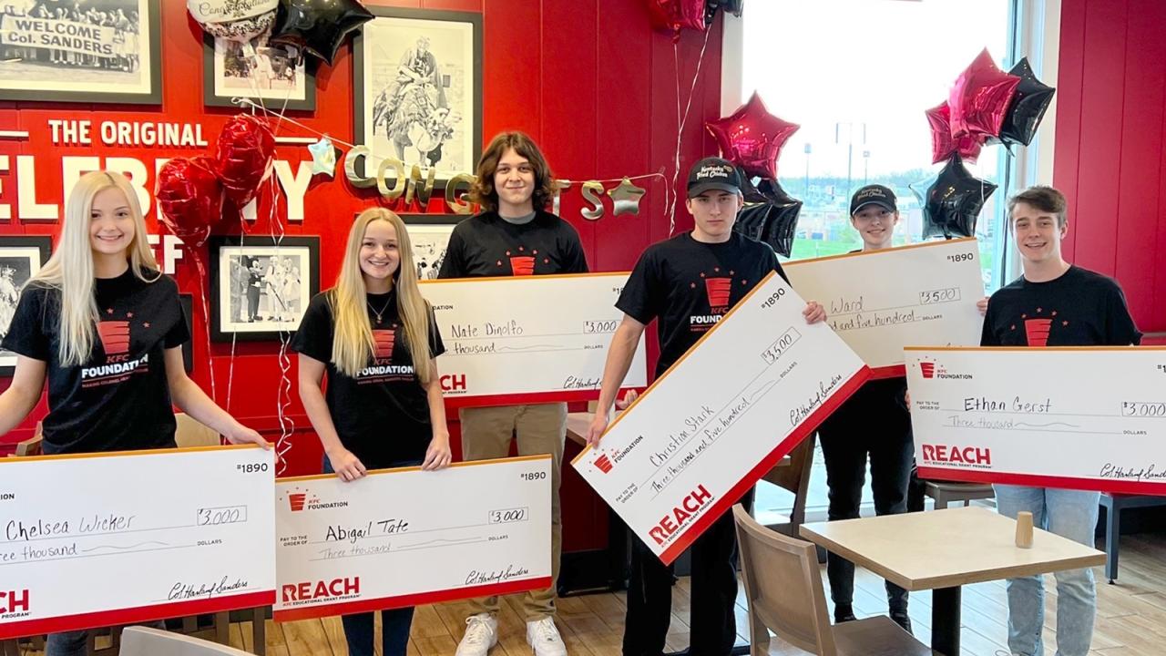 6 students holding big checks