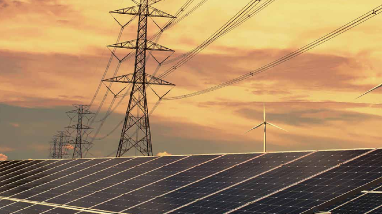 A long row of solar panels under large power lines