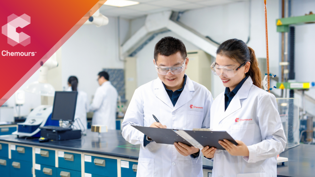 Two people in white coats looking at clipboard together